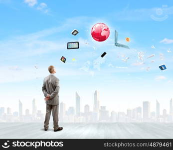 Business vision. Back view of confident businessman looking at city with items flying in air