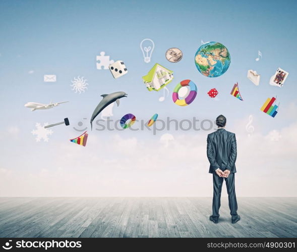 Business vision. Back view of confident businessman looking at city with items flying in air. Elements of this image are furnished by NASA