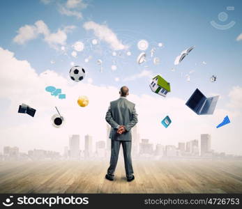 Business vision. Back view of confident businessman looking at items flying in air