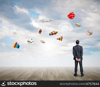 Business vision. Back view of confident businessman looking at items flying in air