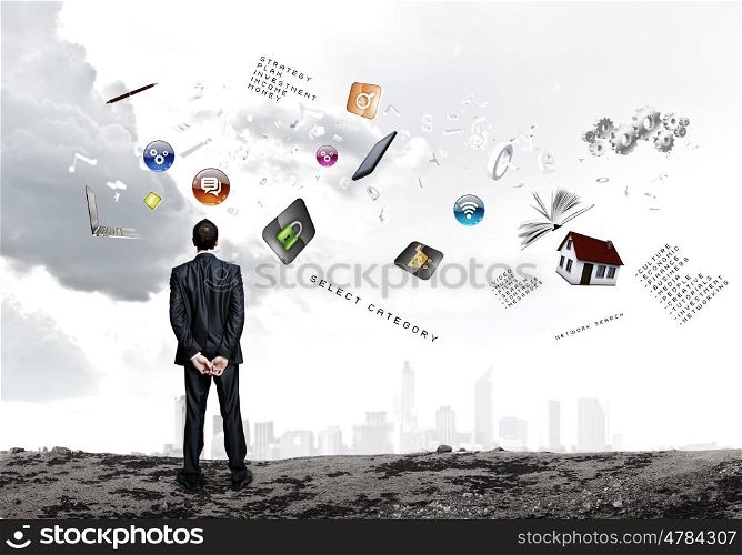 Business vision. Back view of confident businessman looking at items flying in air