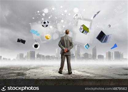Business vision. Back view of confident businessman looking at items flying in air. Elements of this image are furnished by NASA