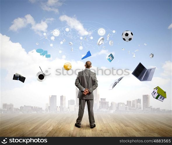Business vision. Back view of confident businessman looking at items flying in air