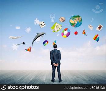 Business vision. Back view of confident businessman looking at items flying in air. Elements of this image are furnished by NASA