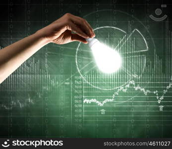 Business vision. Close up of hand holding light bulb with sketches at background