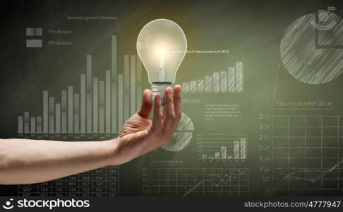 Business vision. Close up of hand holding light bulb with sketches at background