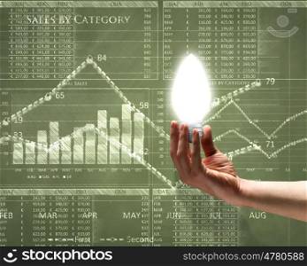 Business vision. Close up of hand holding light bulb with sketches at background