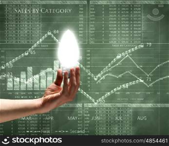 Business vision. Close up of hand holding light bulb with sketches at background