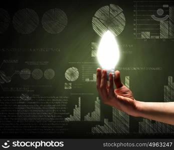 Business vision. Close up of hand holding light bulb with sketches at background