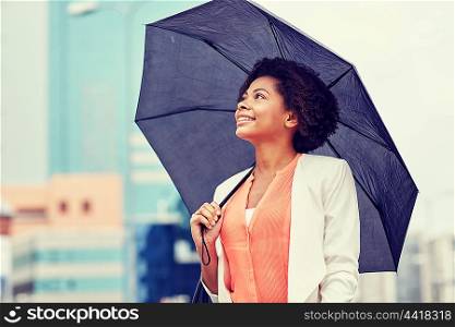 business, weather and people concept - young smiling african american businesswoman with umbrella on city street