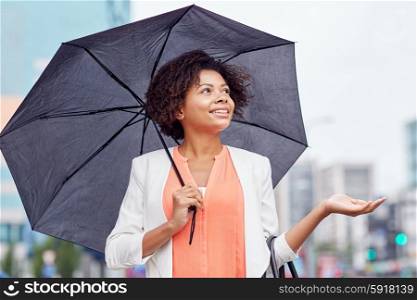 business, weather and people concept - young smiling african american businesswoman with umbrella on city street