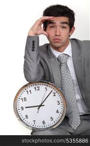 Business with clock suffering from headache