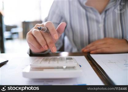 Business woman analyzing investment charts and pressing calculator buttons over documents. Accounting Concept