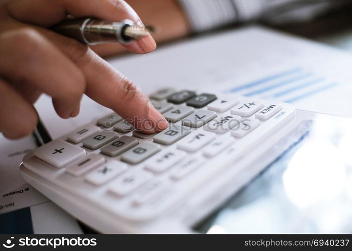 Business woman analyzing investment charts and pressing calculator buttons over documents. Accounting Concept