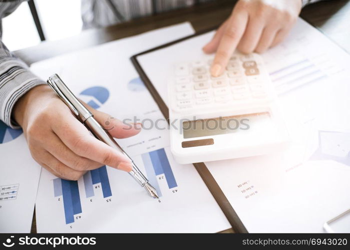 Business woman analyzing investment charts and pressing calculator buttons over documents. Accounting Concept