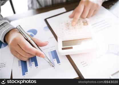 Business woman analyzing investment charts and pressing calculator buttons over documents. Accounting Concept
