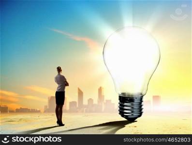 Business woman and ecology issue. Image of businesswoman looking at light bulb. Green energy concept