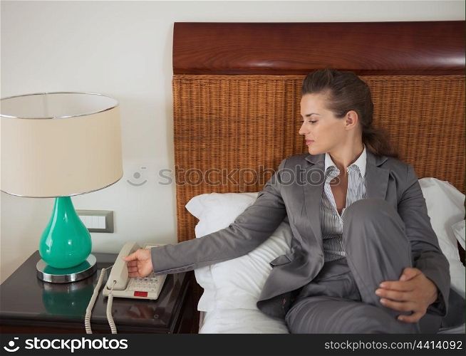 Business woman answering phone call on bed in hotel room