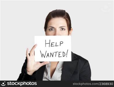 Business woman asking for help holding a cardboard with the text message  Help Wanted 