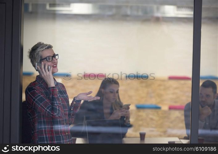 business woman at modern startup office interior talking by phone, people group team on meeting in background