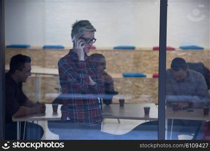 business woman at modern startup office interior talking by phone, people group team on meeting in background