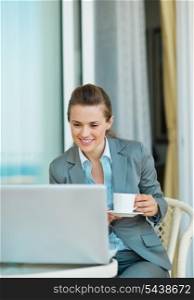 Business woman drinking coffee and looking in laptop