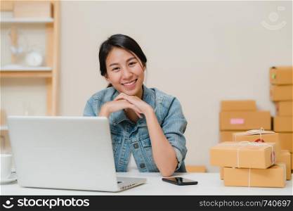 Business woman feeling happy smiling and looking to camera while working in her office at home. Beautiful Asian young entrepreneur owner of SME with small business owner at home office concept.