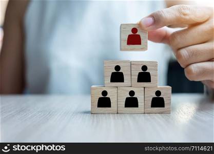 Business woman hand placing or pulling Red Person wooden block on the building. People, Business, Human resource management, Recruitment, Teamwork and strategy Concepts