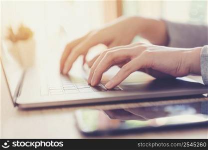 Business woman hand typing laptop computer on wooden table