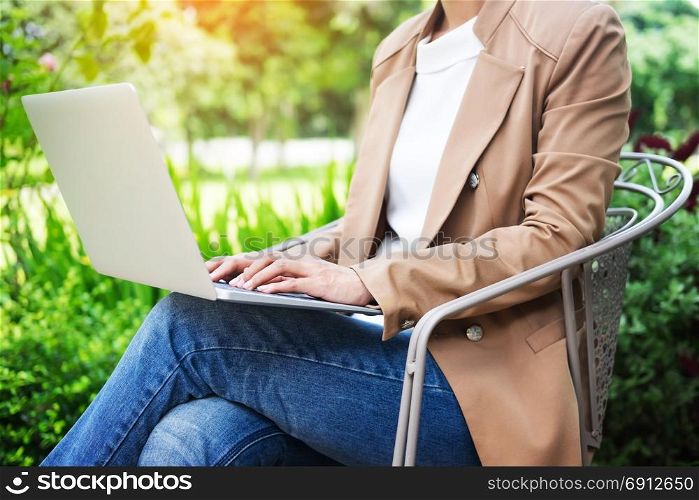 business woman hand using laptop on table in garden
