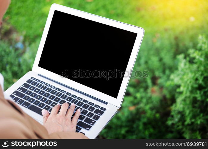 business woman hand using laptop on table in garden