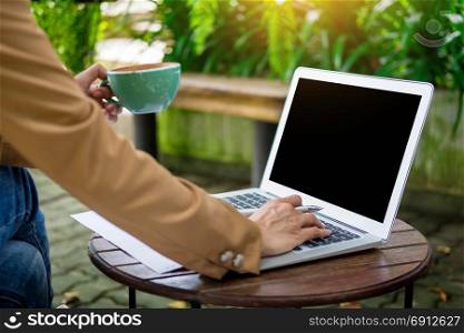 business woman hand working using laptop on table in garden