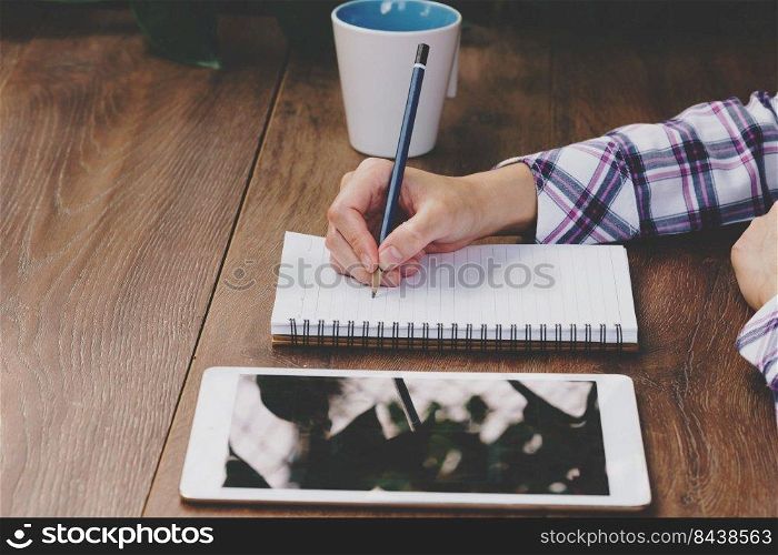 Business woman hand writing notebook on wood table.