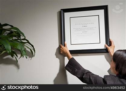 Business woman hanging framed certificate