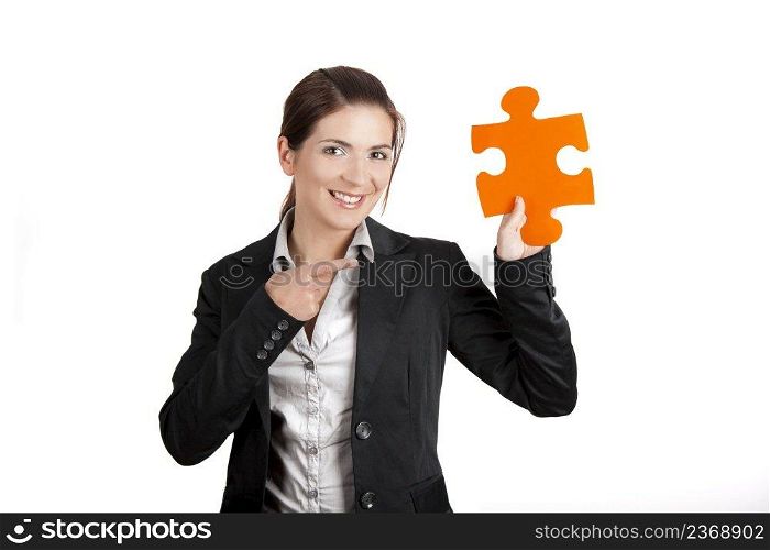 Business woman holding and pointing to a puzzle piece, isolated on white