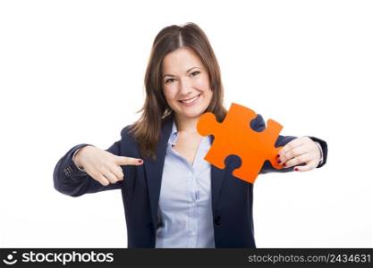 Business woman holding and pointing to a puzzle piece, isolated over white