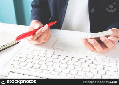 Business woman holding mobile phone and using laptop