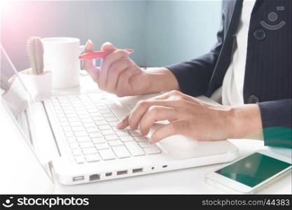 Business woman holding mobile phone and using laptop