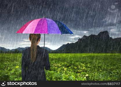 business woman holding multicolored umbrella with falling rain at Khao Jeen Lae, Lopburi, Thailand
