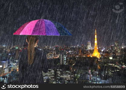 business woman holding multicolored umbrella with falling rain at tokyo city background, Japan