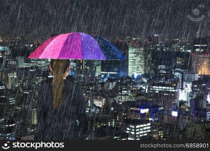 business woman holding multicolored umbrella with falling rain at tokyo city background, Japan