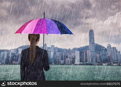 business woman holding multicolored umbrella with falling rain at victoria harbour, Hong Kong