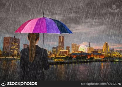 business woman holding multicolored umbrella with falling rain at Yokohama city, Japan