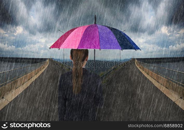 business woman holding multicolored umbrella with falling rain on cross road spliting in two way