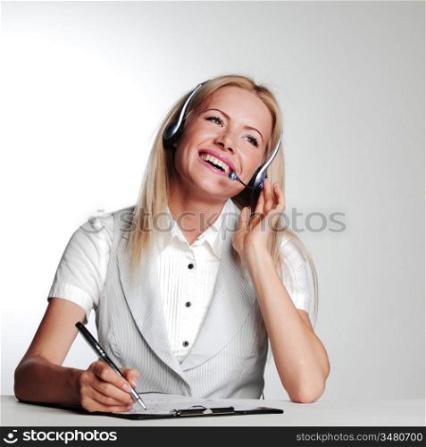 business woman in a headset writing in notebook