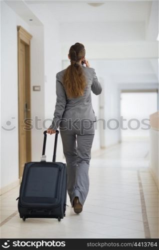 Business woman in business trip with wheel bag. Rear view