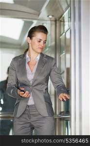 Business woman in elevator pushing button