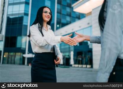 Business woman in glasses and white blouse, handshake with partner outdoor. Modern building, financial center. Successful female businessperson. Business woman, handshake with partner outdoor
