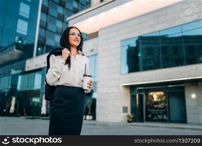 Business woman in glasses, suit and coffee in hand. Modern building, financial center, cityscape. Successful female businessperson. Business woman in glasses, suit and coffee in hand
