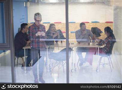 business woman in meeting room speaking by cell phone, people groupbrainstorming in background